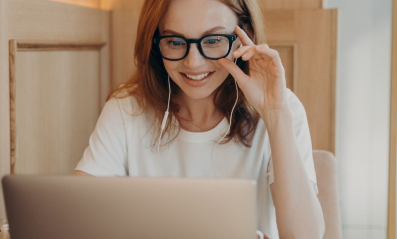 Woman with red hair and glasses looking at laptop